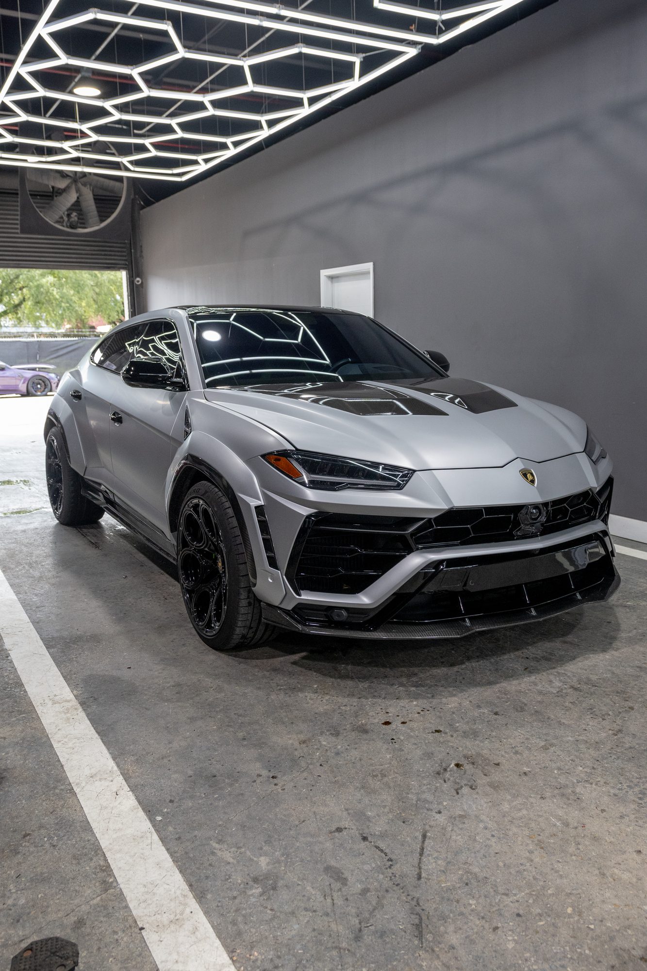 Matte grey Lamborghini Urus with carbon body kit inside the shop